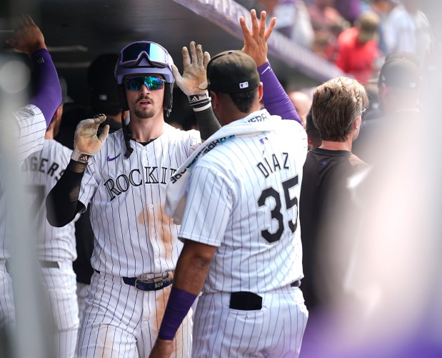 Colorado Rockies' Brenton Doyle, center, is congratulated as he returns to the dugout after hitting a grand slam off Boston Red Sox relief pitcher Chase Anderson in the sixth inning of a baseball game on July 24, 2024, in Denver. (AP Photo/David Zalubowski)