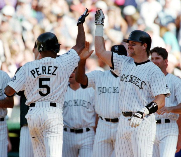 Colorado Rockies' Neifi Perez (5) is congratulated by Larry Walker, right, as the rest of the team comes to meet Perez as he crosses home plate after hitting a solo home run to give the Rockies a 9-8 victory over the San Francisco Giants in the ninth inning in Denver's Coors Field on Sunday, Sept. 27, 1998. (AP Photo/Jack Dempsey)