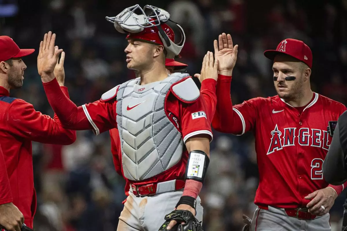 Los Angeles Angels' Logan O'Hoppe, left, and Mike Trout, right greet their teammates at the end of a baseball game against the Cleveland Guardians, Friday, May 30, 2025, in Cleveland. (AP Photo/Phil Long)