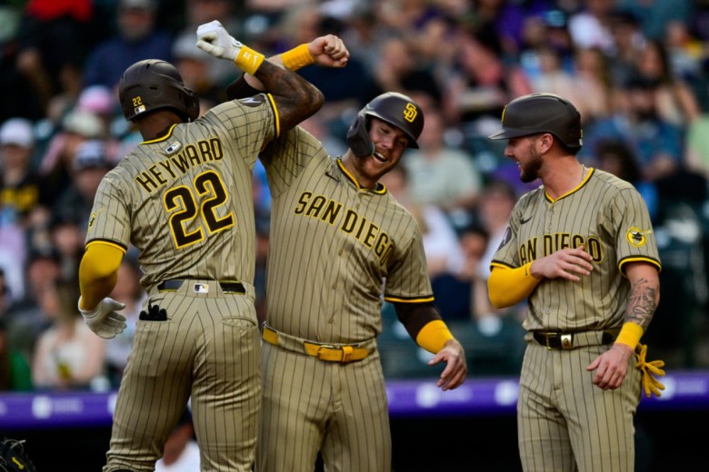 Three men in Padres uniforms celebrate after a home run.