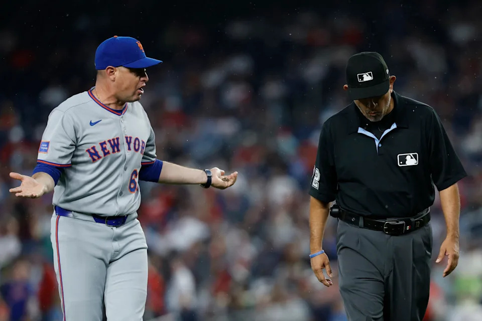 New York Mets manager Carlos Mendoza (64) and umpire Alfonso Marquez (72)© Geoff Burke-Imagn Images