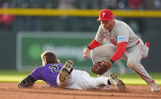 Colorado Rockies' Jordan Beck, left, slides safely into second base with a double as Philadelphia Phillies shortstop Trea Turner, right, applies a late tag in the third inning of a baseball game Monday, May 19, 2025, in Denver. (AP Photo/David Zalubowski)