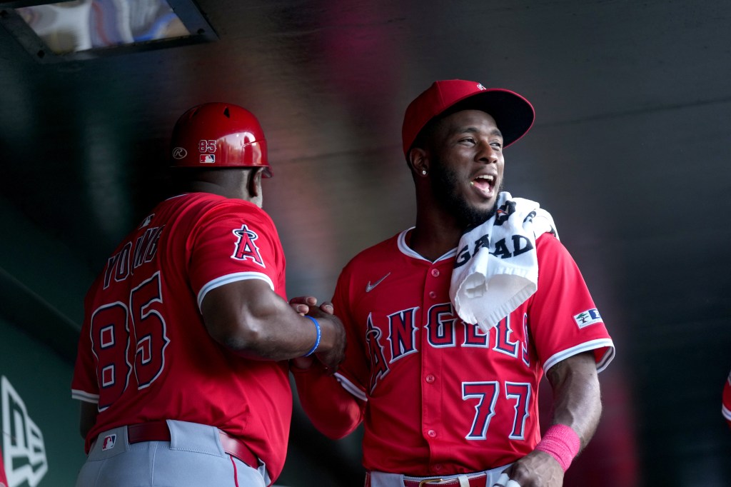 Los Angeles Angels second baseman Tim Anderson (77) greets first base coach Eric Young Sr. (85) in the dugout before a game against the Athletics at Sutter Health Park. 