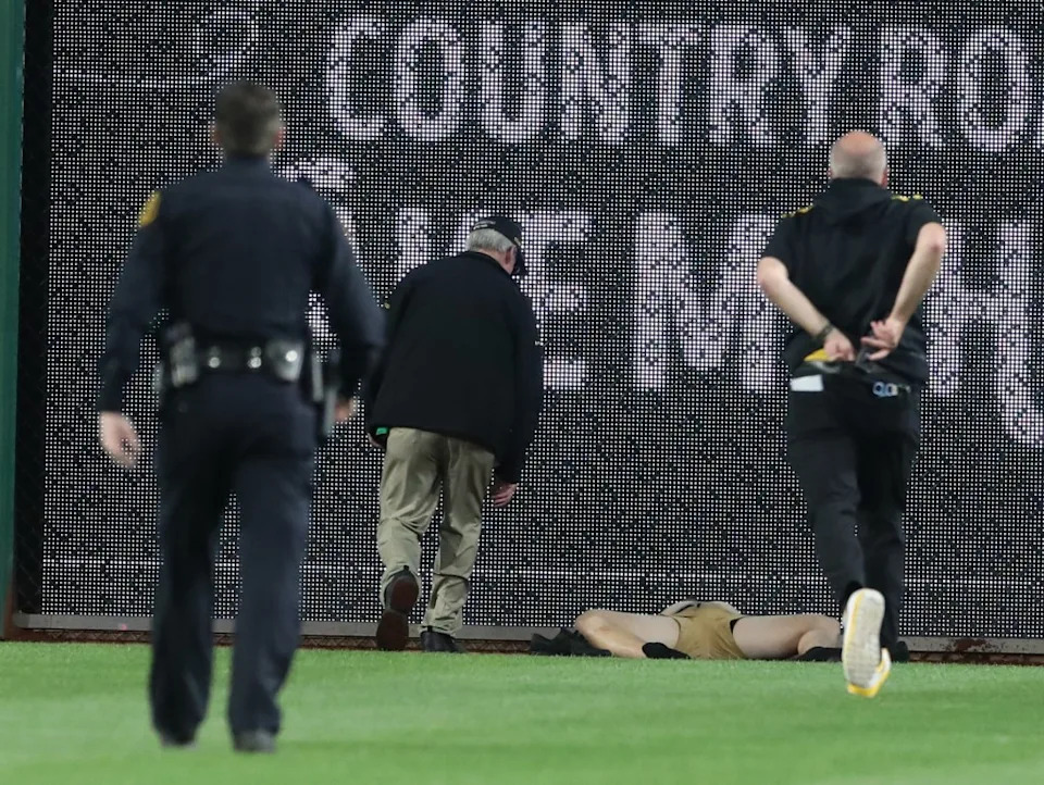 Stadium security and Pittsburgh Pirates medical personnel rush to assist a fan who fell from the stands to the field. Charles LeClaire-Imagn Images