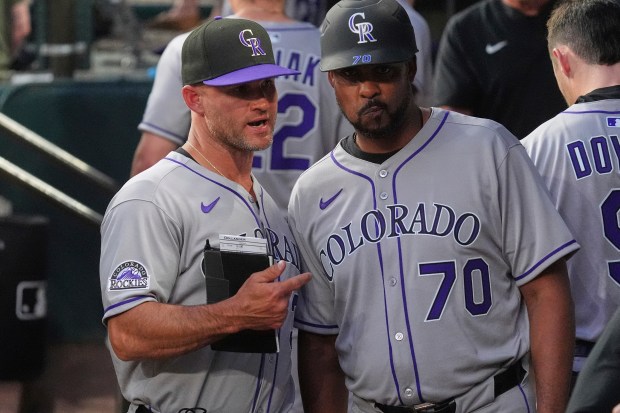 Colorado Rockies interim manager Warren Schaeffer, left, talks with third base coach Andy González (70) in the dugout during the fourth the inning of a baseball game against the Texas Rangers, Monday, May 12, 2025, in Arlington, Texas. (AP Photo/LM Otero)