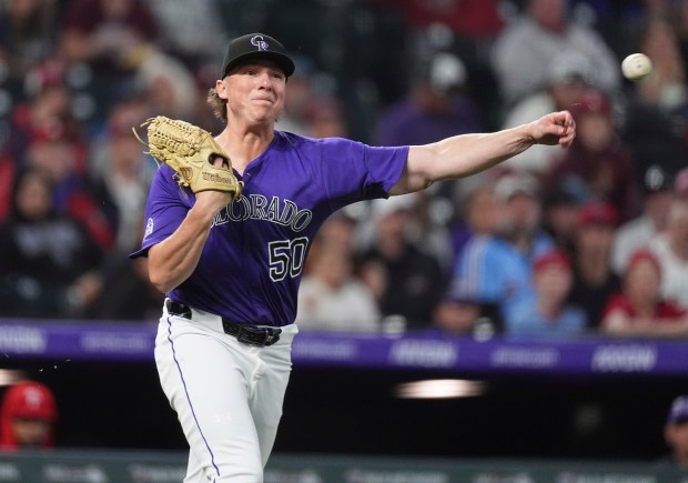 Colorado Rockies relief pitcher Ryan Rolison turns to throw the ball to first base but commits an error after fielding an infield hit off the bat of Philadelphia Phillies' Nick Castellanos in the seventh inning of a baseball game Tuesday, May 20, 2025, in Denver. (AP Photo/David Zalubowski)
