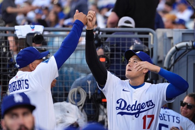 Dodgers manager Dave Roberts, left, greets designated hitter Shohei Ohtani...