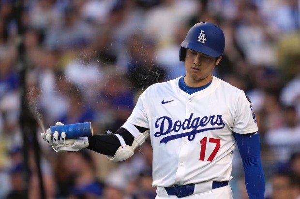Dodgers star Shohei Ohtani sprays a substance from a can...