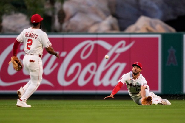 Angels center fielder Matthew Lugo, right, fields a ball hit...