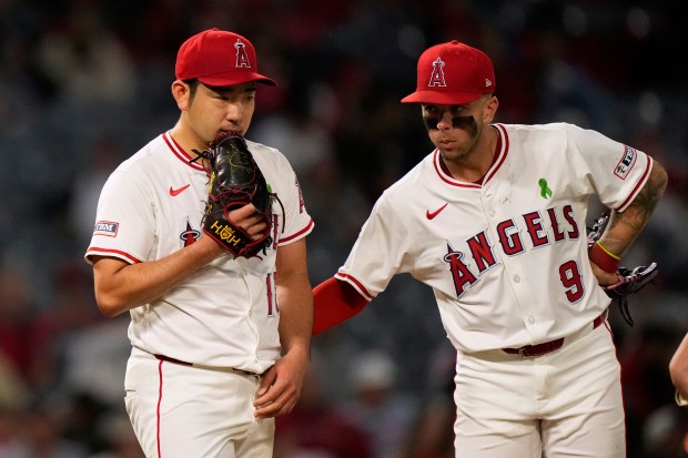 Angels starting pitcher Yusei Kikuchi, left, gets a pat on...