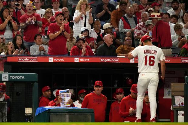 Fans applaud as Angels starting pitcher Yusei Kikuchi walks back...