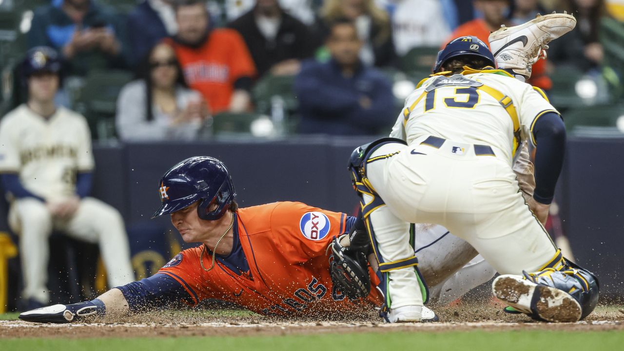 Houston Astros' Zach Dezenzo slides safety into home plate ahead of the tag by Milwaukee Brewers' Eric Haase (13) during the fifth inning of a baseball game, Wednesday, May 7, 2025, in Milwaukee. (AP Photo/Jeffrey Phelps)
