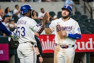 Texas Rangers' Jake Burger celebrates a run with Texas Rangers' Adolis Garcis during the...