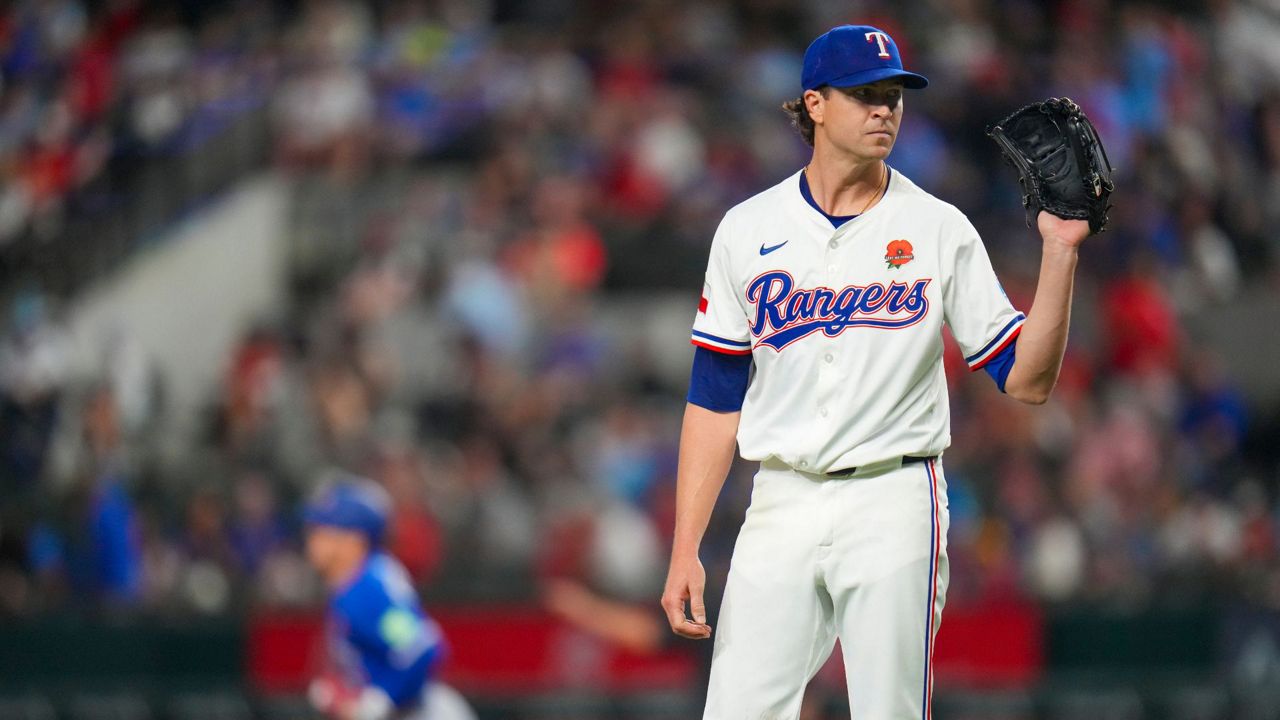 Texas Rangers starting pitcher Jacob deGrom, right, waits for a new ball as Toronto Blue Jays' Daulton Varsho, left, runs the bases after hitting a solo home run during the first inning of a baseball game, Monday, May 26, 2025, in Arlington, Texas. (AP Photo/Julio Cortez)
