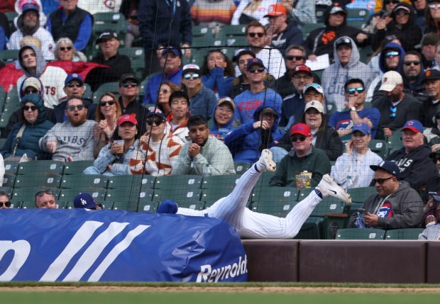 Chicago Cubs second baseman Nico Hoerner chases an overthrown ball behind the tarp in the ninth inning Wednesday, May 7, 2025, at Wrigley Field. (Brian Cassella/Chicago Tribune)