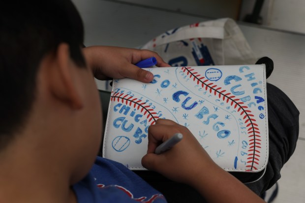 A young Cubs fan decorates a scrapbook before a Cubs-White Sox game on May 17, 2025, at Wrigley Field. (John J. Kim/Chicago Tribune)