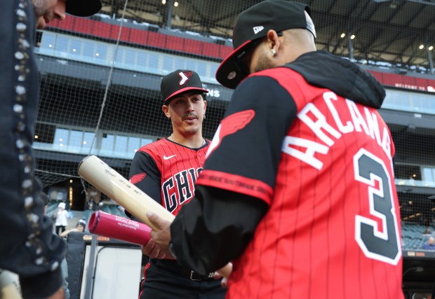 White Sox first baseman Miguel Vargas, center, gifts signed bats to reggaeton artist Arcángel before a White Sox-Rangers game at Rate Field on May 23, 2025, in Chicago. (John J. Kim/Chicago Tribune)