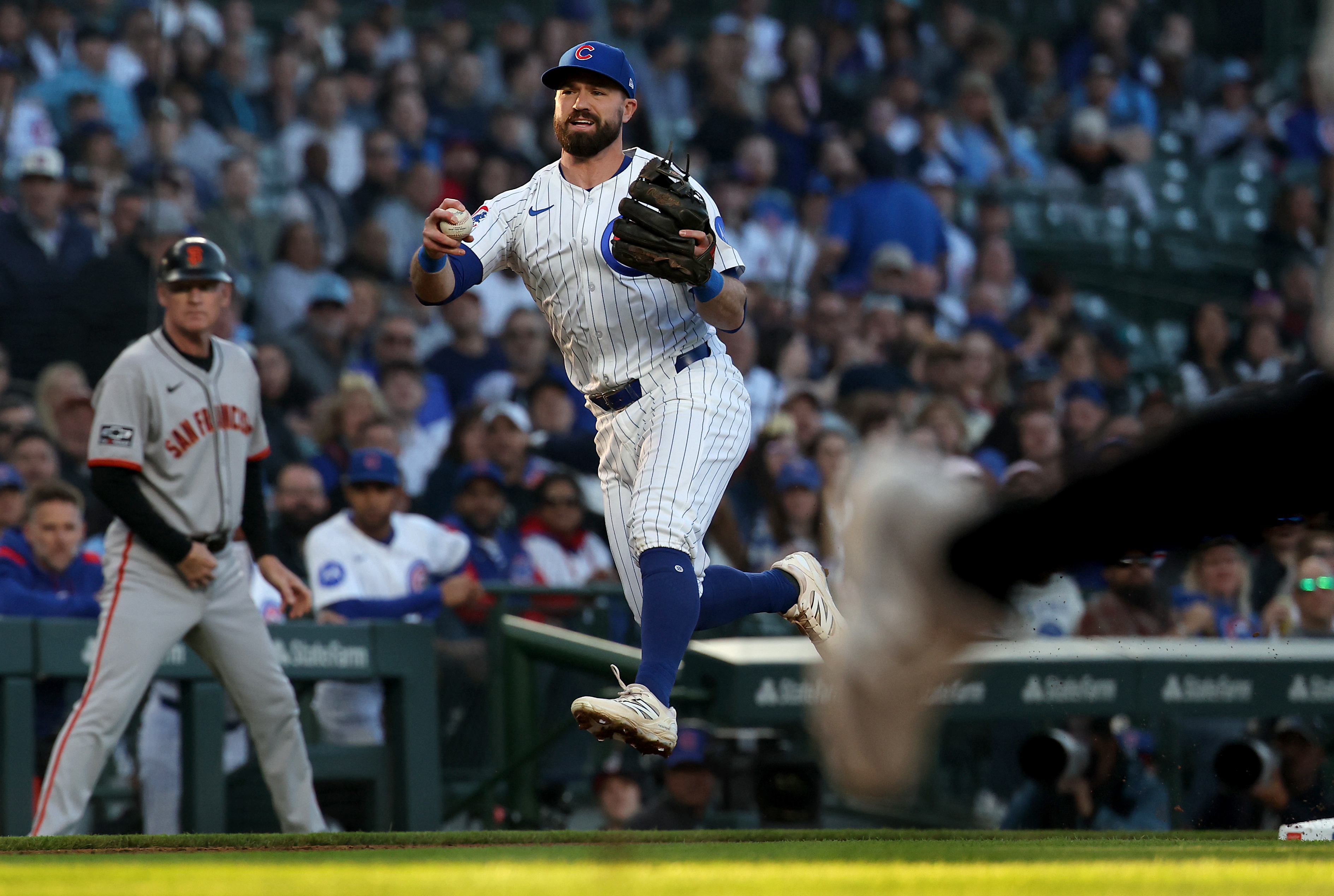 Chicago Cubs third baseman Jon Berti pauses on making a throw on an infield ground ball in the second inning before following through on a throw to first base that resulted in an error in the second of a game against the San Francisco Giants at Wrigley Field in Chicago on May 6, 2025. The Giants scored a run on the play. (Chris Sweda/Chicago Tribune)