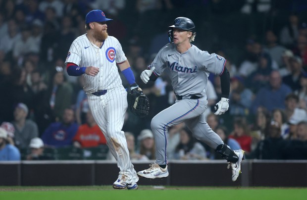 Miami Marlins center fielder Kyle Stowers sprints past Chicago Cubs first baseman Justin Turner (left) en route to a triple in the ninth inning of a game at Wrigley Field in Chicago on May 14, 2025. (Chris Sweda/Chicago Tribune)