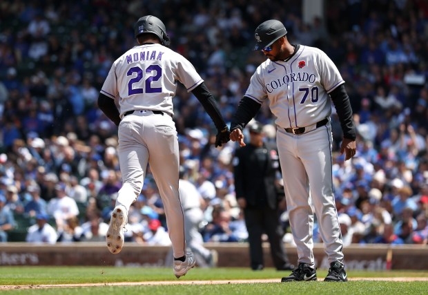 Colorado Rockies outfielder Mickey Moniak (22) is congratulated by third base coach Andy González (70) after Moniak hit a solo home run in the fifth inning of a game against the Chicago Cubs at Wrigley Field in Chicago on May 26, 2025. (Chris Sweda/Chicago Tribune)