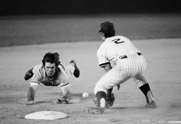 Pete Rose of the Cincinnati Reds slides head first, feet in the air, as he races the ball for third base with a seventh inning triple at Shea Stadium in New York, Aug. 13, 1976. New York Mets third baseman Roy Staiger, right, awaits the late throw from rightfielder Mike Vail. (AP Photo/Ray Stubblebine)