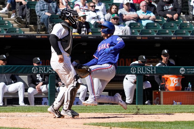 Texas Rangers' Kyle Higashioka, right, scores as Chicago White Sox catcher Edgar Quero, left, looks on during the ninth inning of a baseball game Sunday, May 25, 2025, in Chicago. (AP Photo/David Banks)