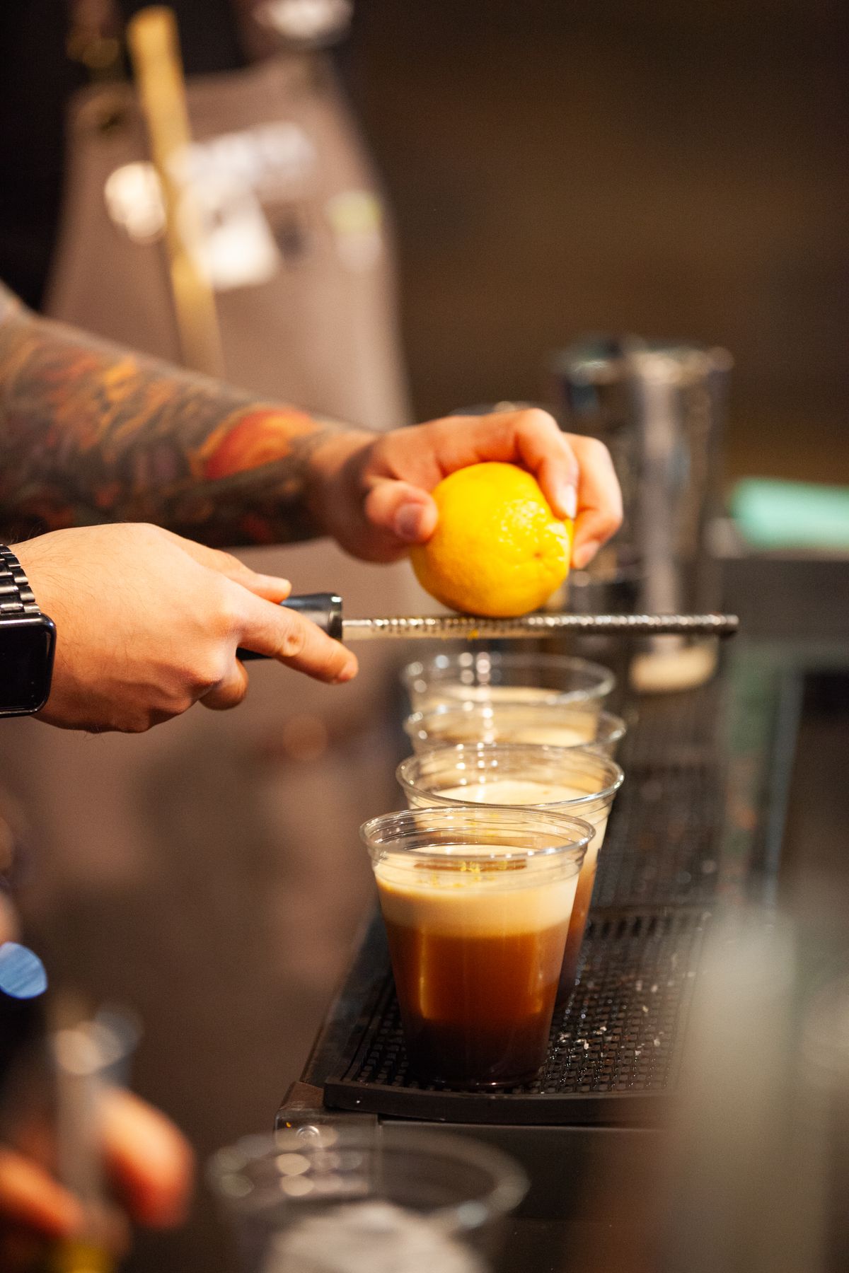 A bartender grates an orange over carajillos.