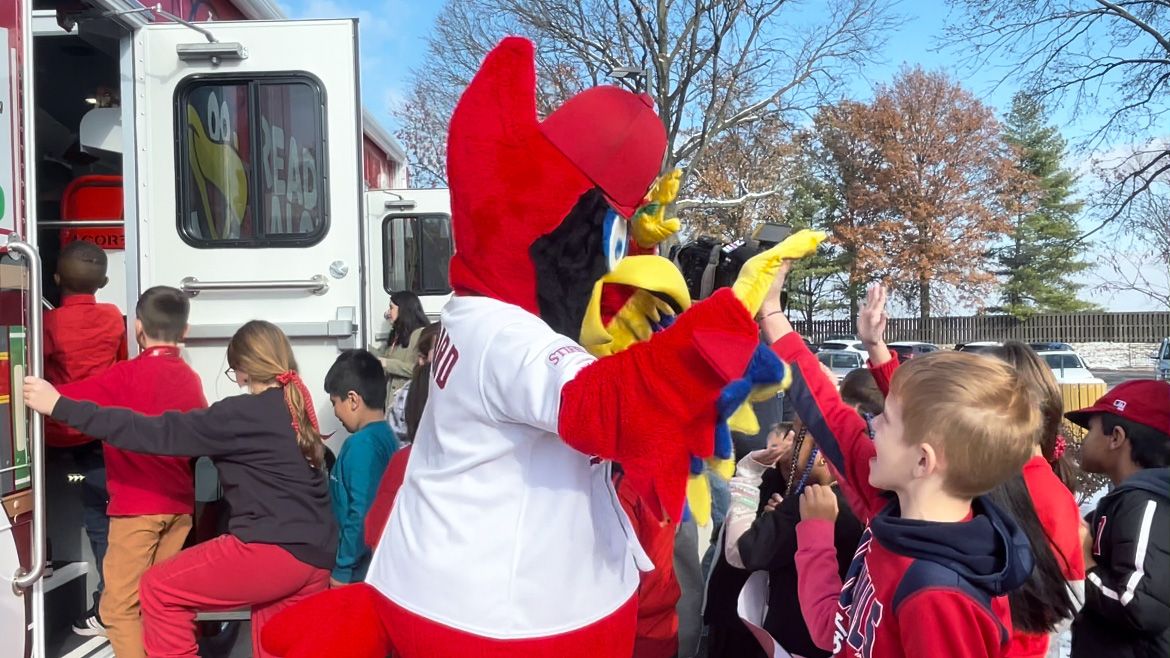 Fredbird greets students at Bierbaum Elementary Tuesday before they enter the new Cardinals-themed bookmobile in partnership with the St. Louis County Library and Cardinals Care. (Spectrum News/Elizabeth Barmeier)
