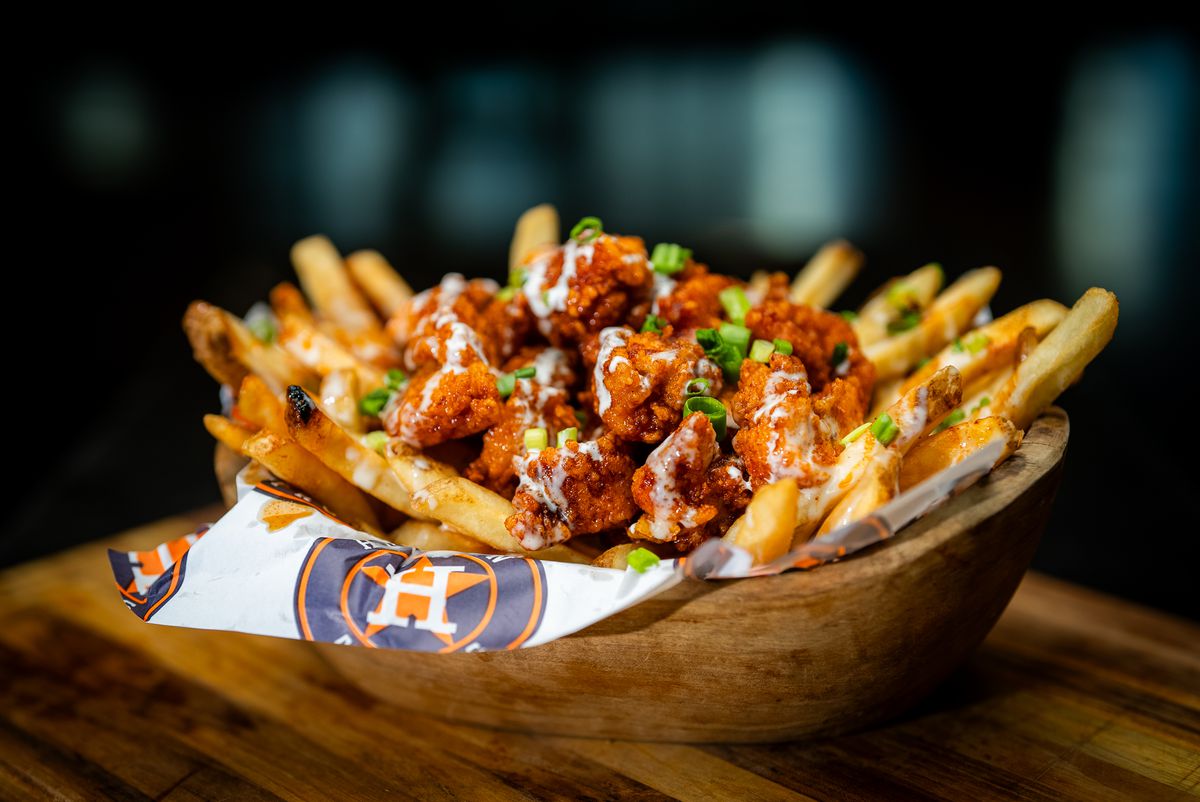 A bed of fries loaded with fried chicken bites and sauces.