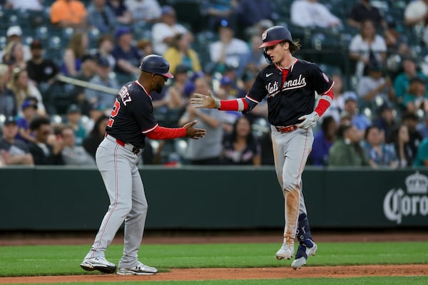 Washington Nationals' Robert Hassell III, right, celebrates his first career home run with third base coach Ricky Gutierrez during the eighth inning of a baseball game against the Seattle Mariners Wednesday, May 28, 2025, in Seattle. (AP Photo/Ryan Sun)