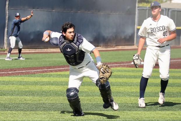 St. John Bosco catcher Micah Taguiam fields a play in...