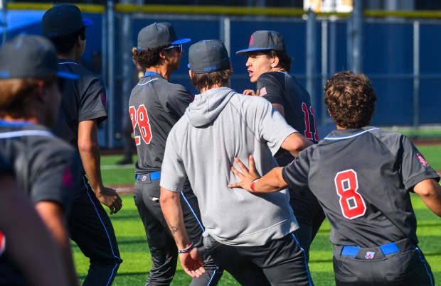 Los Alamitos pitcher Logan Anderson (11) is mobbed by teammates...