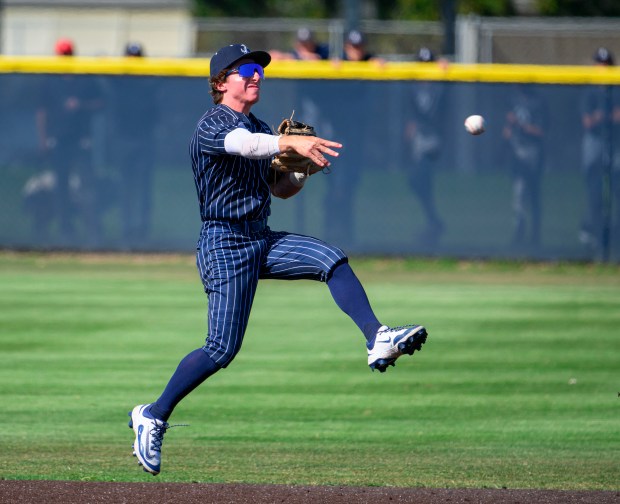 Newport Harbor shortstop Adam Martin turns in the air to...