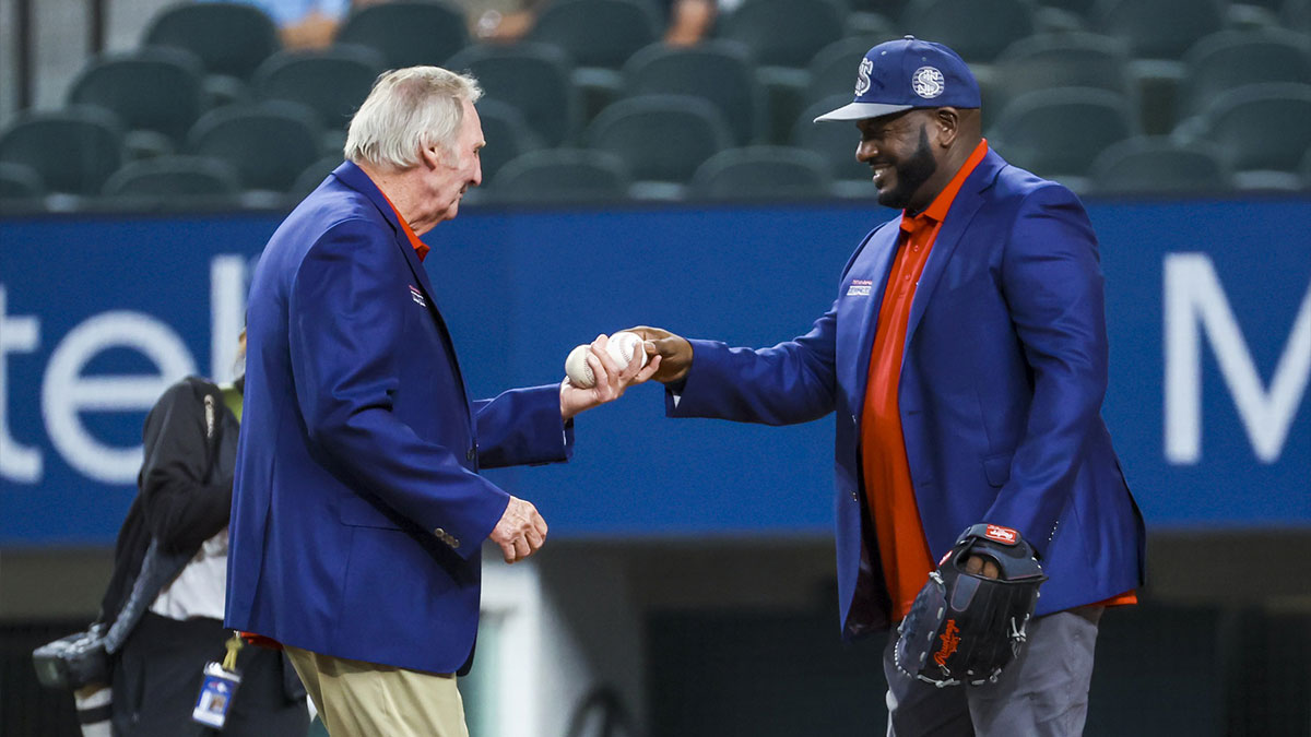 Texas Rangers former pitcher Charlie Hough gets the ball from former player Ruben Sierra after throwing out the ceremonial first pitch before the game against the Washington Nationals at Globe Life Field.