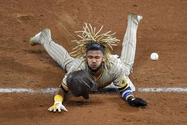 Fernando Tatis Jr. #42 of the San Diego Padres reacts after being hit by the ball on the pickoff attempt after sliding safely into third base with a sixth inning steal against the Colorado Rockies at Coors Field on Aug. 28, 2020 in Denver, Colorado. All players are wearing #42 in honor of Jackie Robinson Day. The day honoring Jackie Robinson, traditionally held on April 15, was rescheduled due to the COVID-19 pandemic. (Photo by Dustin Bradford/Getty Images)