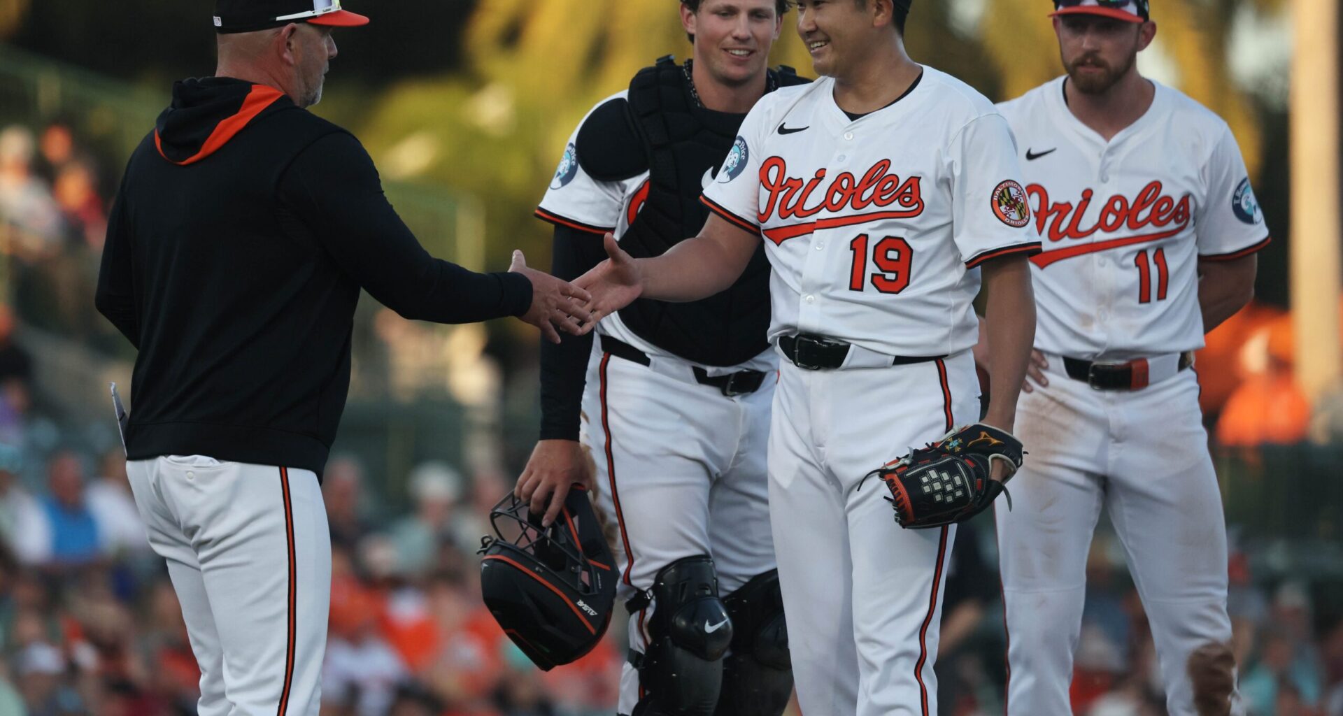 Baltimore Orioles starting pitcher Tomoyuki Sugano (19) smiles as he is taken out of the game by manager Brandon Hyde (18) during the fourth inning against the Minnesota Twins at Ed Smith Stadium.