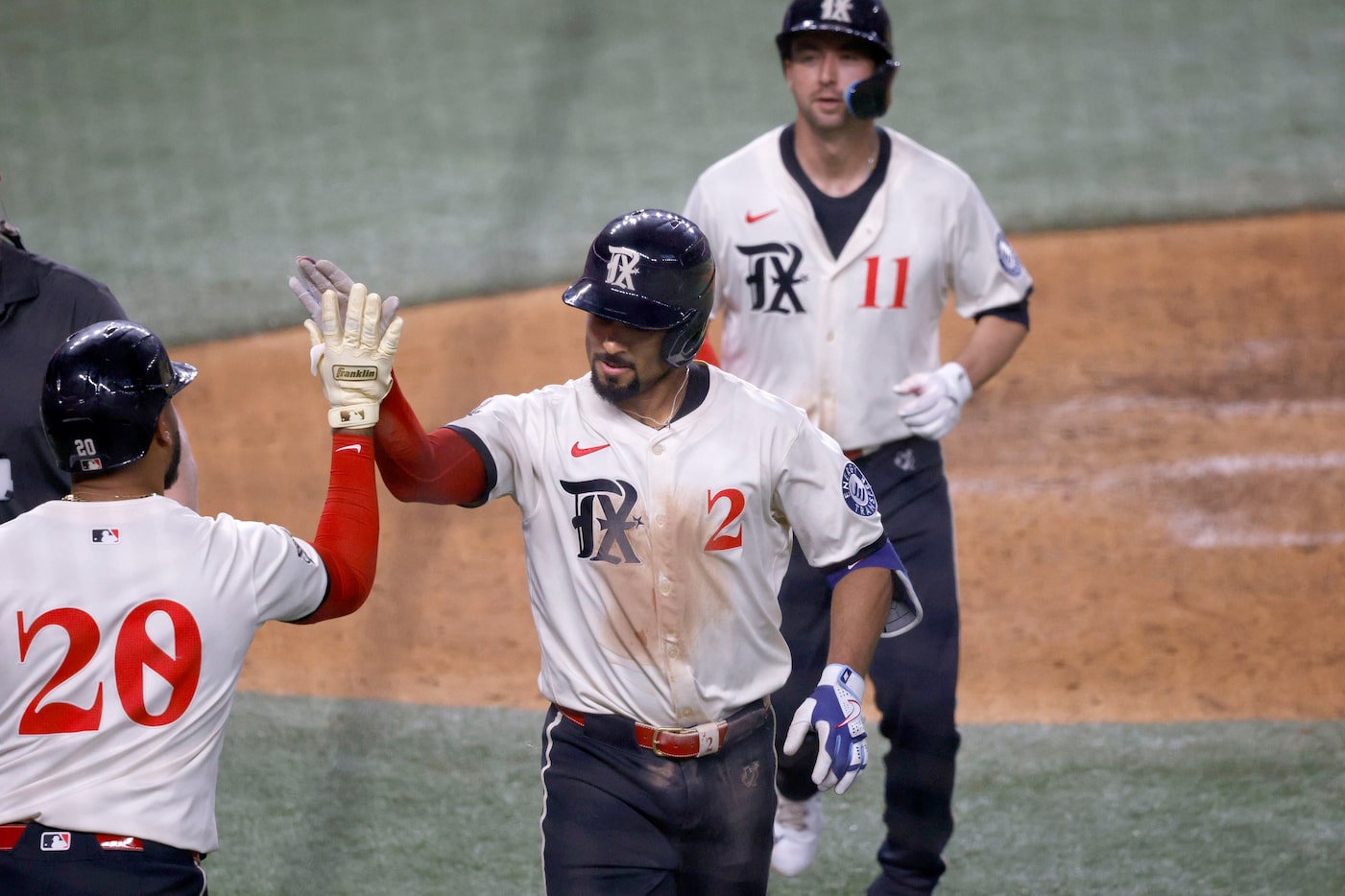 Texas Rangers Marcus Semien (2) gets a high-five from his teammate Ezequiel Duran (20) after...