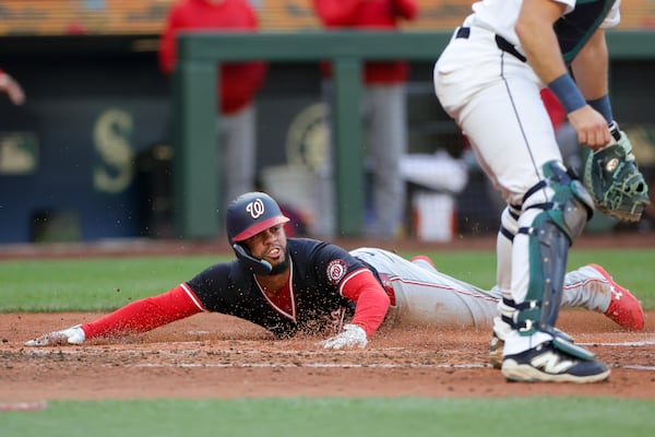 Washington Nationals' Luis Garcia Jr. slides home to score past Seattle Mariners catcher Cal Raleigh off a single hit by Robert Hassell III during the fourth inning of a baseball game Wednesday, May 28, 2025, in Seattle. (AP Photo/Ryan Sun)