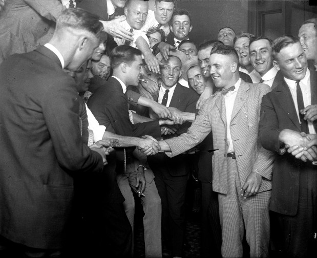 Chicago White Sox players are congratulated after the Black Sox trial in 1921. Eddie Cicotte, second from right front, and Oscar 'Happy' Felsch, right, shake hands with fans as Buck Weaver (center with hat) and several other players and fans smile for the camera. (Chicago Tribune historical photo)
