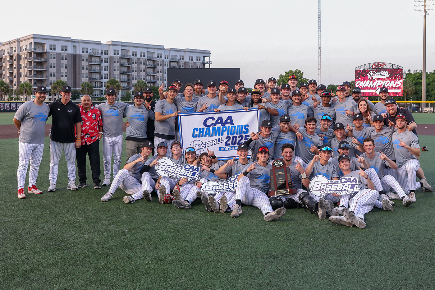Northeastern baseball team posing with a banner that says 'CAA Champions 2025' on it. 