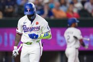 Texas Rangers outfielder Adolis García heads back to the dugout after striking out with...