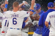 Texas Rangers' Adolis García, center right, covers his face as teammates celebrate after his...