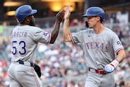 Texas Rangers' Adolis García, left, and Evan Carter celebrate after scoring on a single hit...