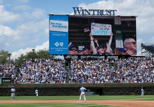 Cubs players warm up for the third inning as fans...