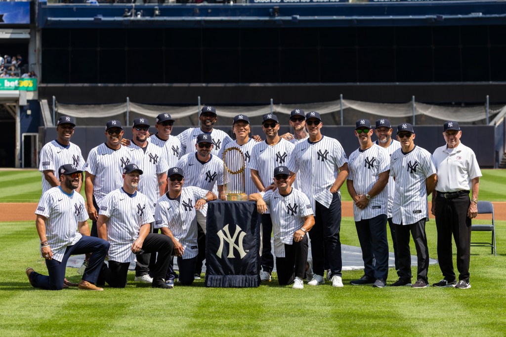 Members of the 2009 World Series team pose on the field with a World Series trophy during Old Timer's Day before a game against the Colorado Rockies, Saturday, Aug. 24, 2024.