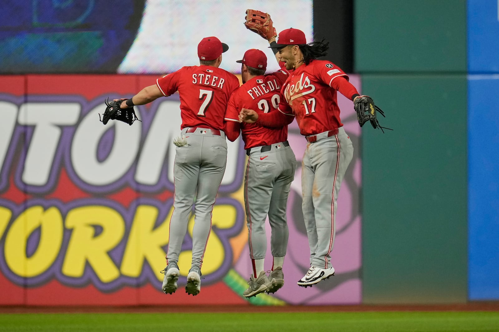 Cincinnati Reds outfielders Spencer Steer (7), TJ Friedl, center, and Connor Joe (17) celebrate after the Reds defeated the Cleveland Guardians in a baseball game in Cleveland, Monday, June 9, 2025. (AP Photo/Sue Ogrocki)