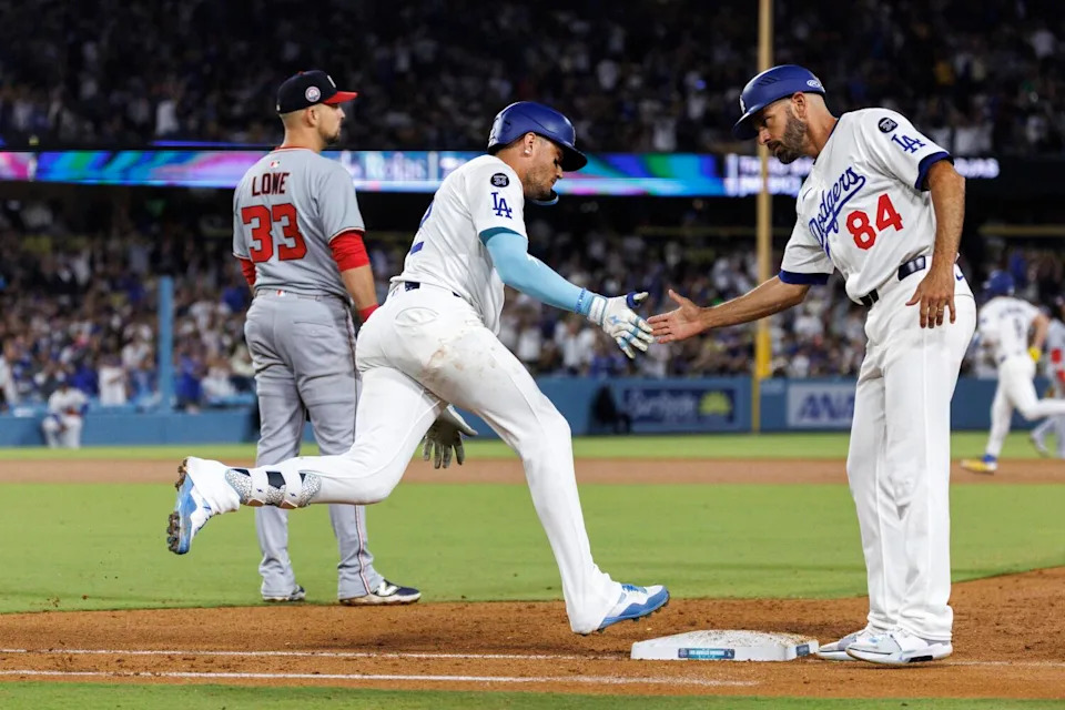 Miguel Rojas, left, gets a hand slap from Dodgers first base coach Chris Woodward.