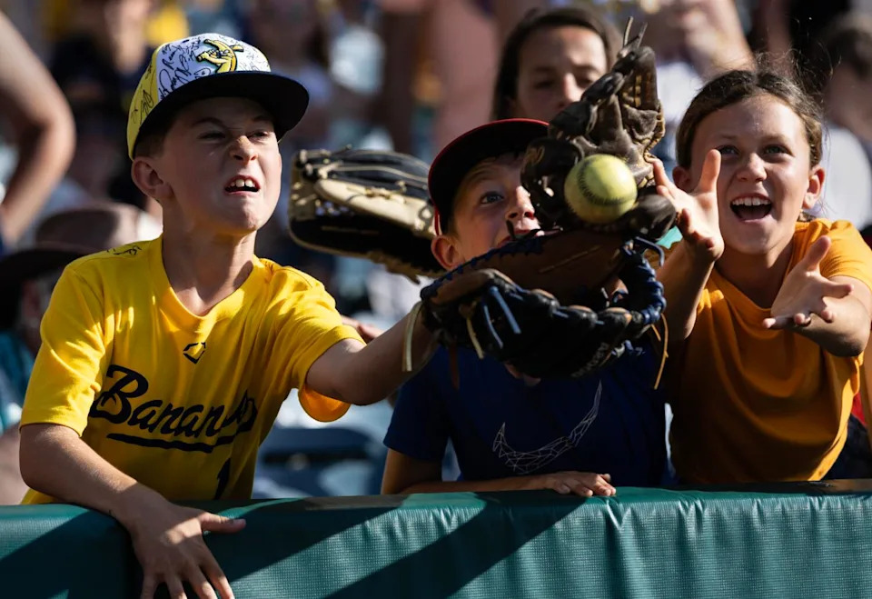 Rainer Easton tries to catch a yellow "Banana Ball" from the stands.