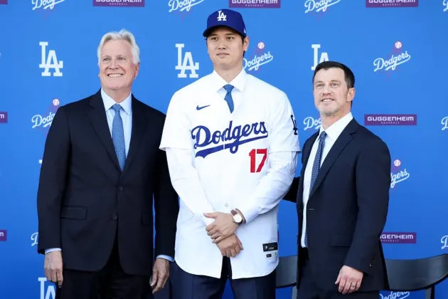 Dodgers owner Mark Walter (left) and president of baseball operations Andrew Friedman (right) stand for a photo with Shohei Ohtani (center) in December 2023. Walter has reportedly agreed to buy the Lakers.