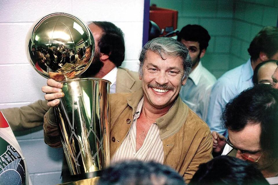 Lakers owner Jerry Buss celebrates with the Larry O'Brien Trophy after the team's 1980 NBA championship victory.